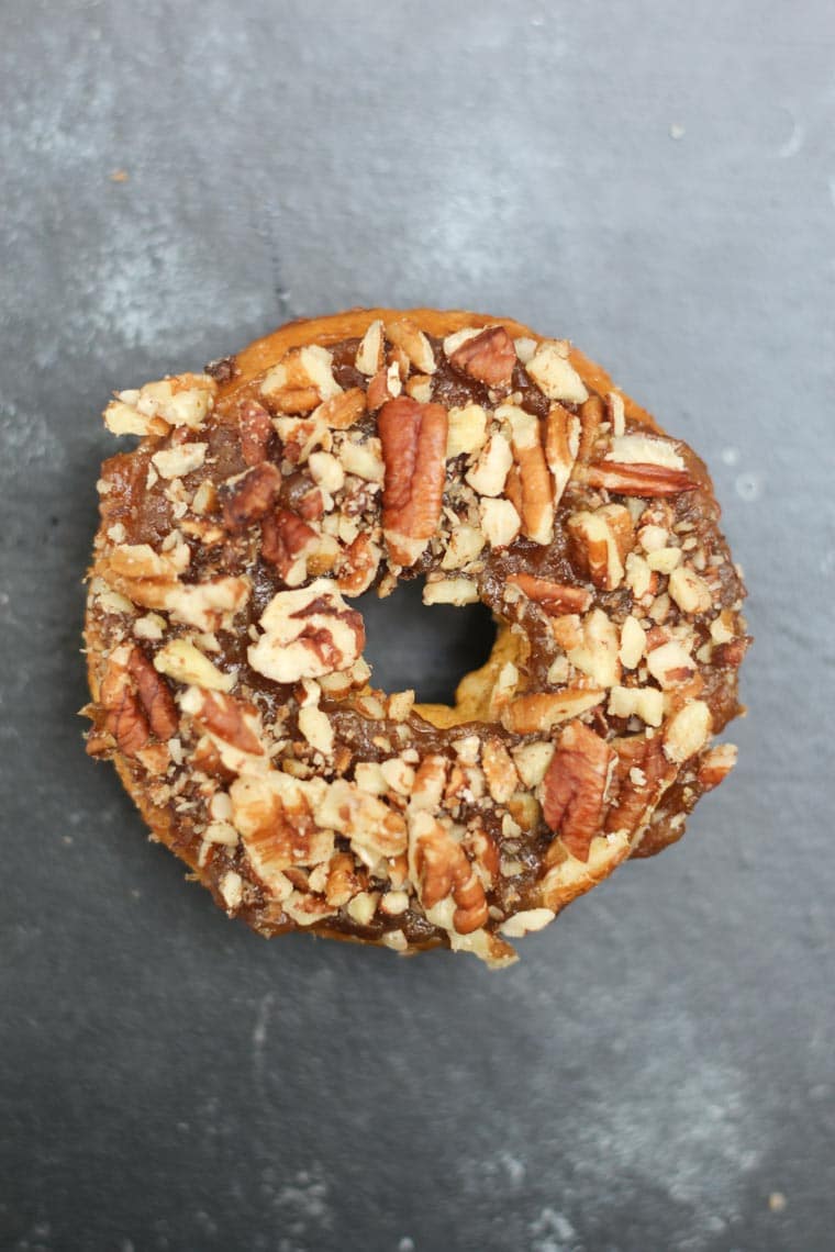 birds eye view of vegan and gluten free pumpkin donut on a grey surface topped with nuts