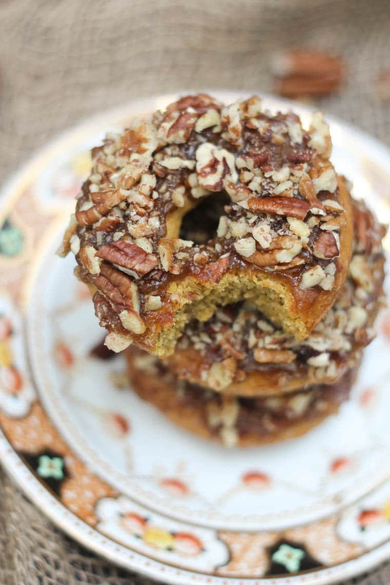 stack of vegan and gluten free pumpkin donuts topped with nuts on a colourful plate
