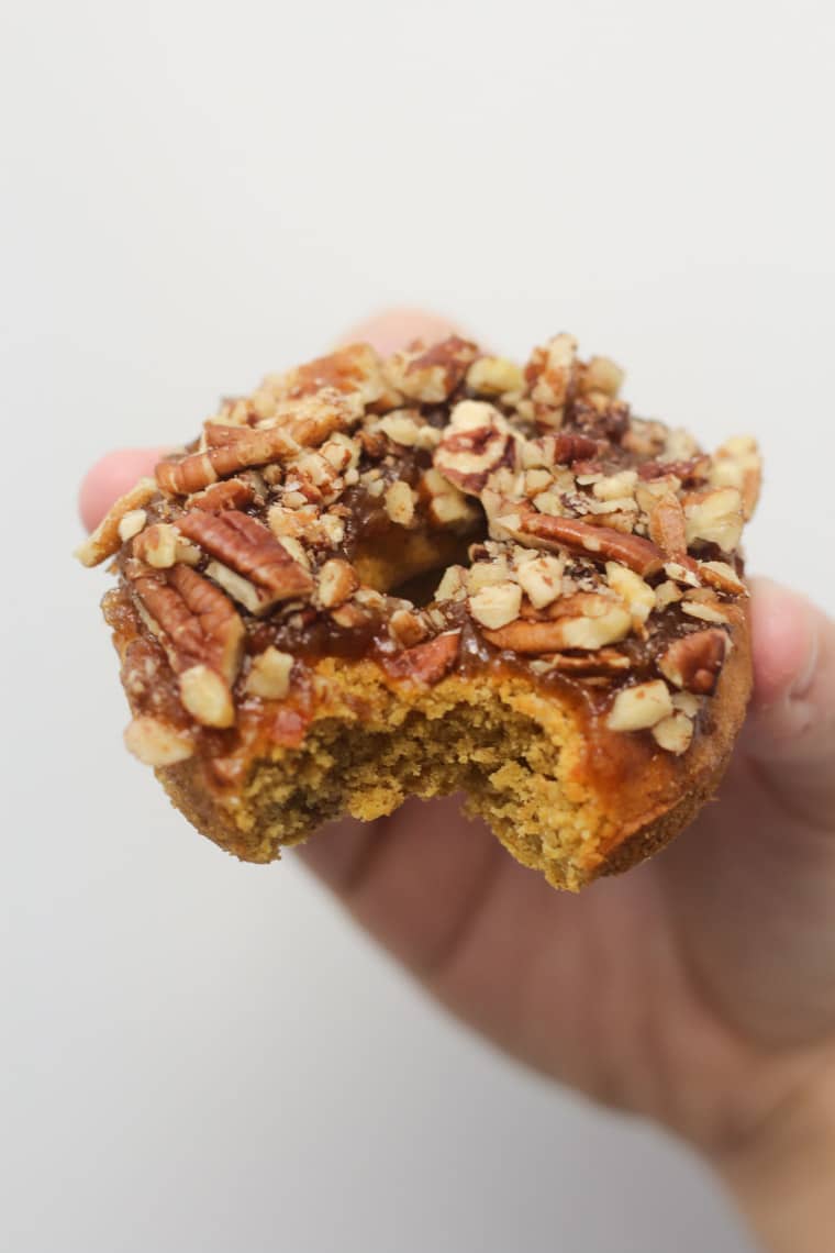 hand holding a thanksgiving flavoured donut garnished with nuts