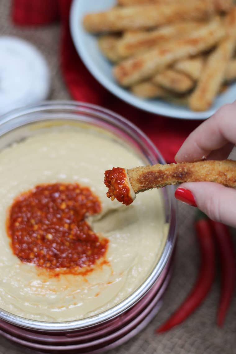 Dipping food into a container of hummus.