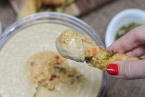 A pesto pizza twist being dipped into hummus.
