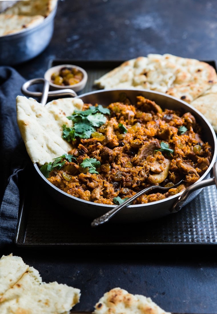 Meat in a black skillet with pita bread.