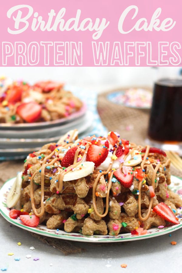 Pinterest image of a stack of birthday cake protein waffles on a white plate with strawberries and sprinkles on top with the text overlay \"Birthday Cake Protein Waffles.\" 