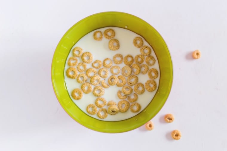 A green bowl with milk and cereal. 