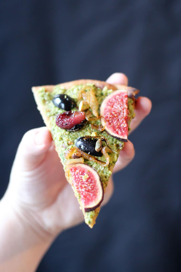 hand holding a slice of vegan olive flatbread