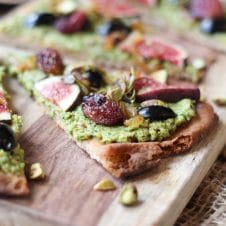 Vegan Olive Pesto Flatbread with Olives from Spain, Roasted Grapes and Figs This Vegan Olive Pesto Flatbread with Olives from Spain, Roasted Grapes and Figs is a perfect plant-based healthy holiday appetizer to feed a crowd! Serves 16 Gordal olives from Spain Pesto 1/2 cup pistachios (shelled) 1 cup pitted Gordal olives from Spain 1 garlic clove, minced 1 cup arugula ¼ cup extra virgin olive oil Pepper, to taste Flatbread 3 tbsp extra virgin olive oil, divided ½ onion, thinly sliced 1 ½ cups red grapes 2 sprigs rosemary 6 small whole grain naan breads 4 figs, thinly sliced ¼ cup pitted Dark Hojiblanca olives from Spain, thinly sliced ¼ cup crushed pistachios In a food processor, puree the pistachios until they reach a powder like consistency, then add in the Gordal olives from Spain, garlic, arugula and oil. Season with pepper, to taste. Set aside. Preheat oven to 450 F. Heat a tablespoon of oil in a nonstick skillet over medium-low heat. Add in the onions and saute until dark and caramelized, about 50 minutes. Set aside. Meanwhile, place the grapes and rosemary on a baking sheet and drizzle with a tablespoon of oil. Place the naans on baking sheets and drizzle with the remaining tablespoon of oil. Roast the grapes for 20-25 minutes or until caramelized, and the flatbread for 5-10 minutes just until toasted around the edges. When ready to serve, smear the olive pesto all along the toasted naans. Top with the roasted grapes, figs, Dark Hojiblanca olives from Spain, caramelized onions and pistachios. Enjoy!