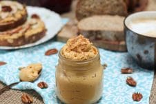 A table with a blue tablecloth with a mason jar filled with pumpkin pie butter inside.