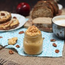 A table with a blue tablecloth with a mason jar filled with pumpkin pie butter inside.