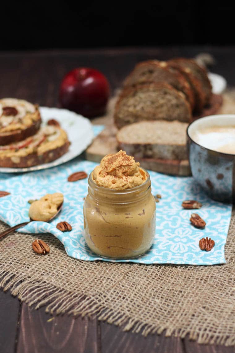 A table with a blue tablecloth with a mason jar filled with pumpkin pie butter inside.