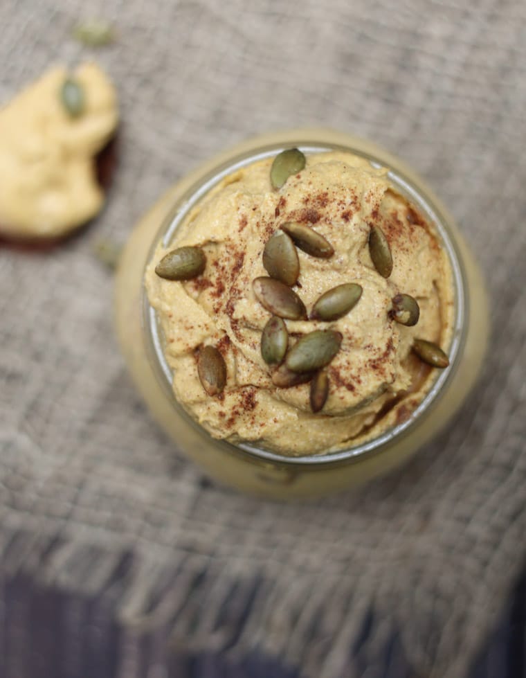 Overhead image of a jar of pumpkin pie butter with some pumpkin seeds on top.