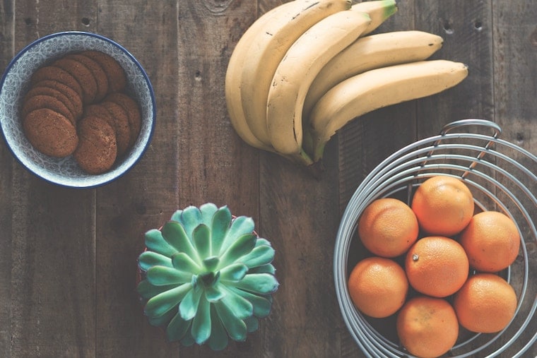 Oranges in a bowl, bananas, and cookies in a bowl on a counter top to increase electrolytes to help relieve stomach cramps. 