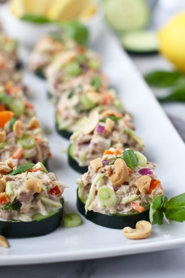 lineup of cashew tuna salad bites on a white pate garnished with herbs