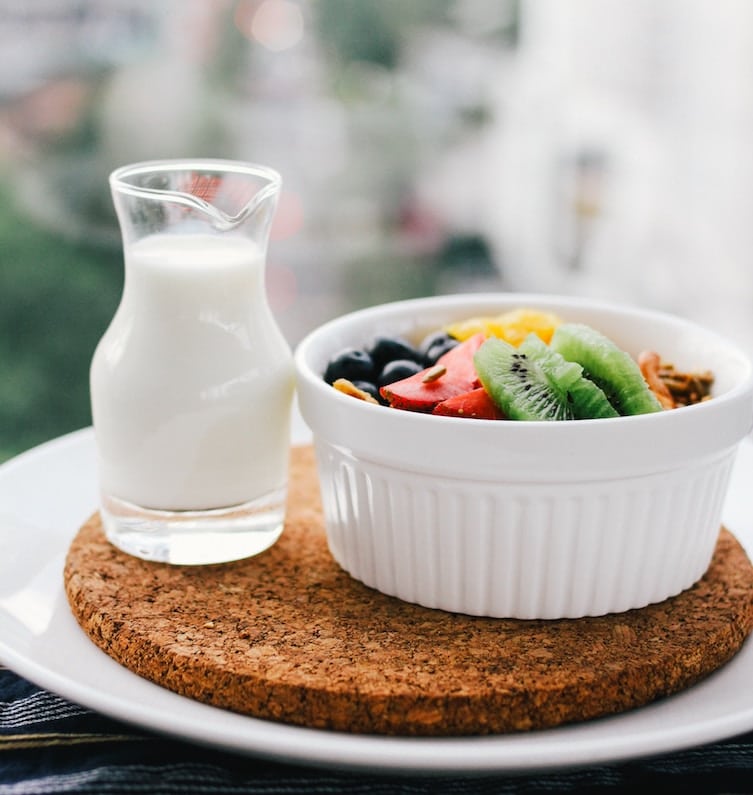 fresh fruit in a small white ramekin next to a clear glass of milk