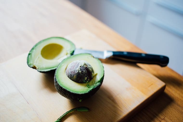 avocado sliced open on a wooden cutting board