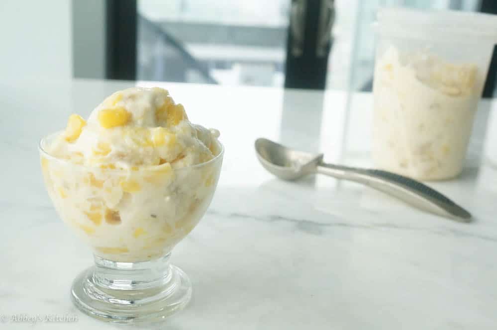 tropical frozen greek yogurt in a clear bowl with a silver spoon