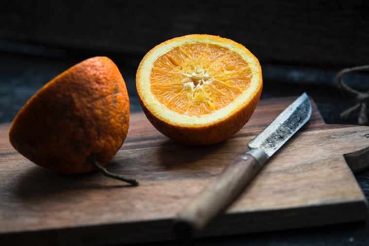orange cut in halves on a wooden cutting board