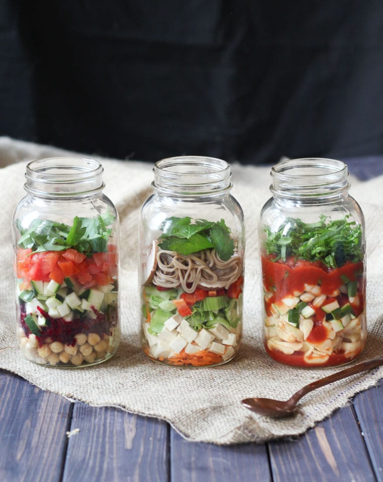three different varieties of vegan mason jar soups in tall clear mason jars