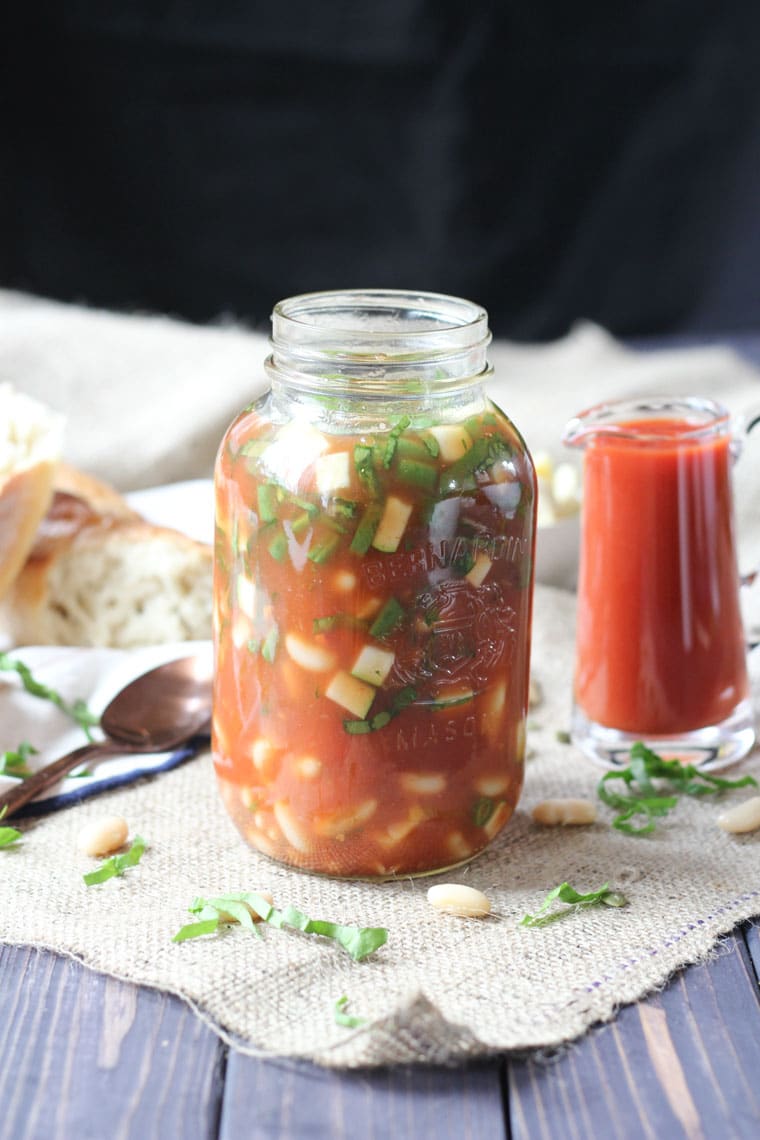 vegan italian pasta mason jar soup garnished with fresh herbs next to a loaf of bread