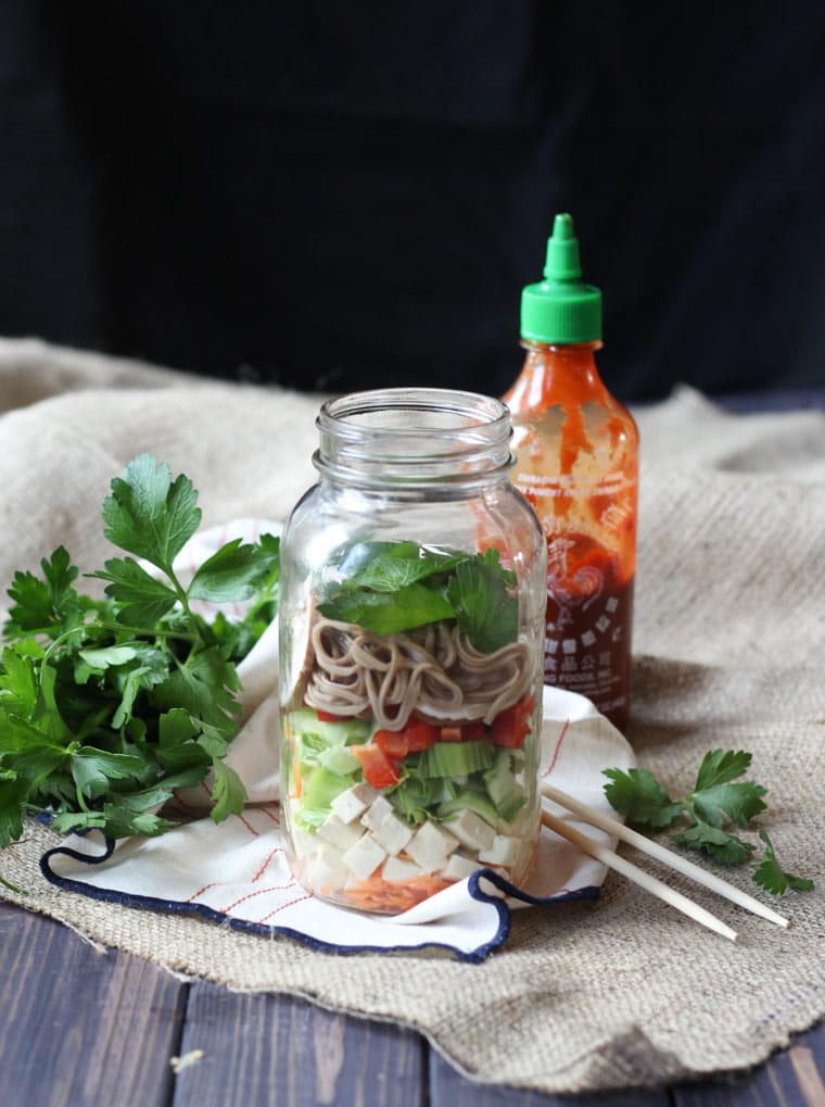 vegan miso noodle soup in a mason jar next to a bottle of hot sauce and fresh cilantro