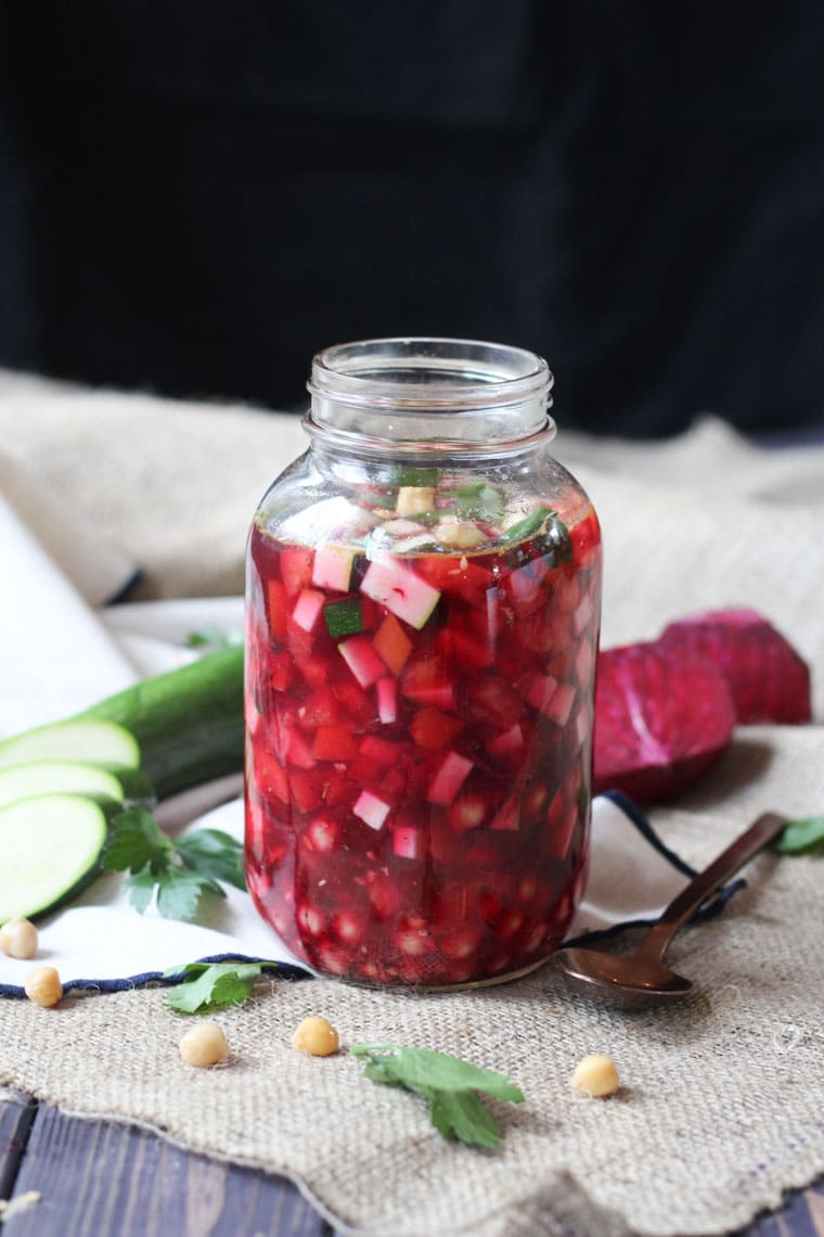 vegan chickpea and beet soup in a tall clear mason jar next to cucumbers and beets