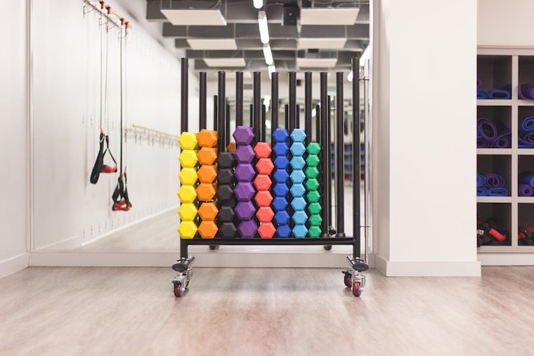 Photo of a rack of multiple colourful small weights. 