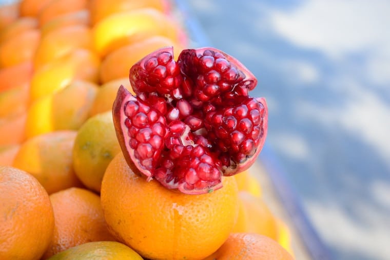 half of a pomegranate on top of oranges