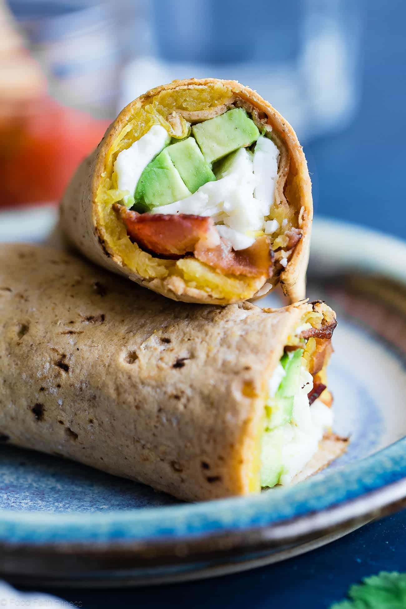 close up of acorn squash breakfast burrito cut in halves on a blue plate