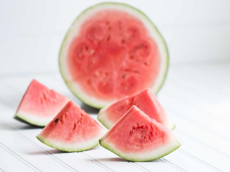 slices of watermelon next to a watermelon half