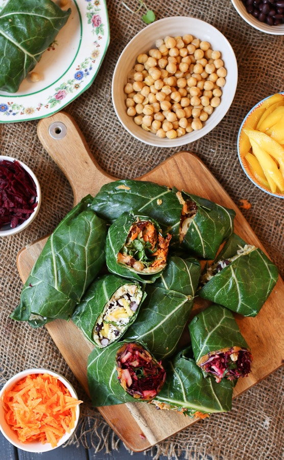 birds eye view of various vegan collard green wraps on a wooden serving board