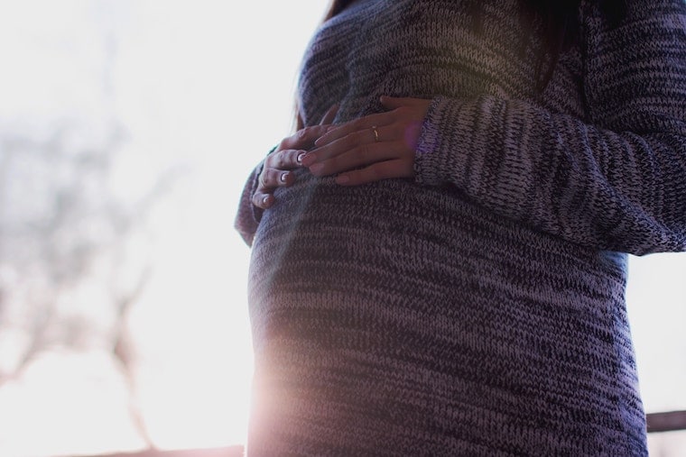 pregnant woman in a dress holding her stomach