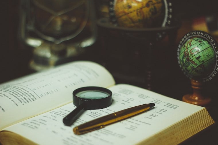 a book with a magnifying glass and a pen on top