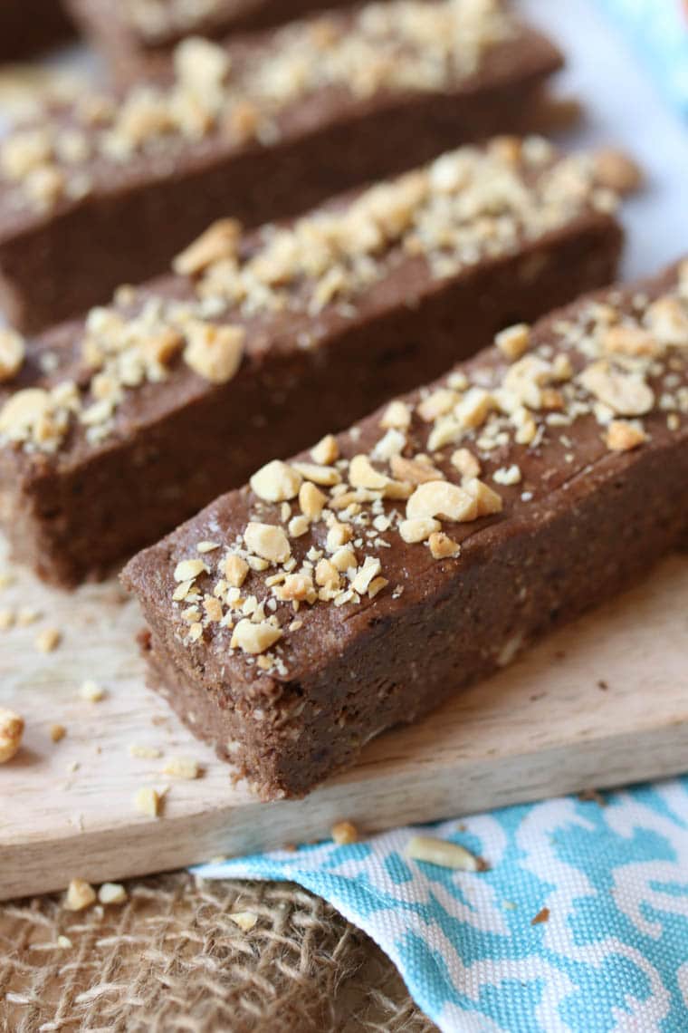 close up of vegan protein bars topped with chopped nuts on a wooden surace