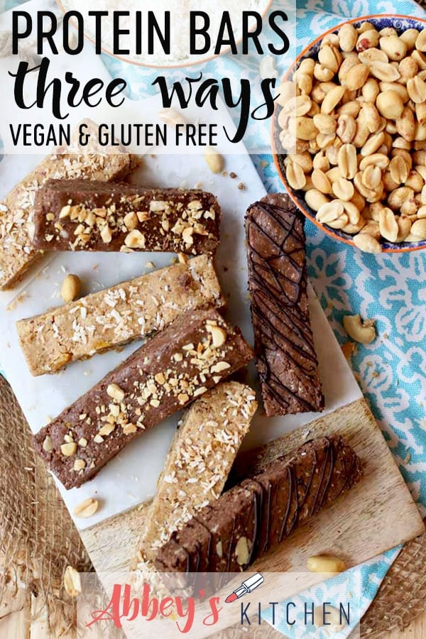Pinterest image of Birds eye view of vegan and gluten free protein bars three ways on a marble cutting board next to a bowl of peanuts with text overlay.