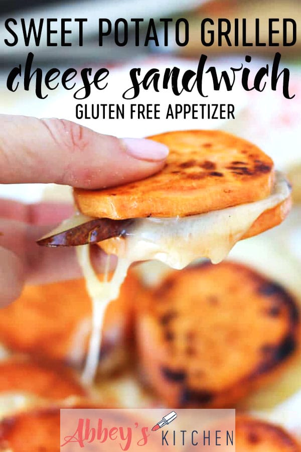 Hand holding two slices of sweet potato with cheese and pear sandwiched in between.