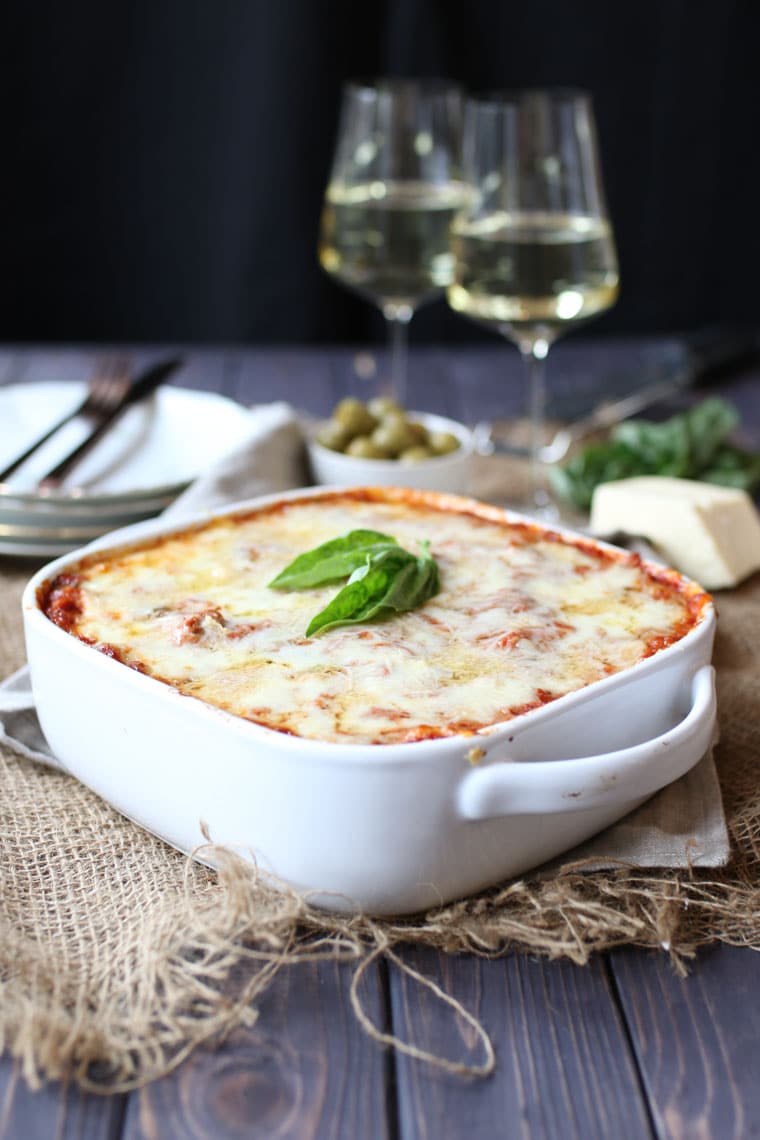 A zucchini lasagna in a white baking dish on a set table.