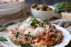 A photo of a slice of zucchini lasagna with turkey sausage ragu with grated cheese on top and basil sprinkled on.