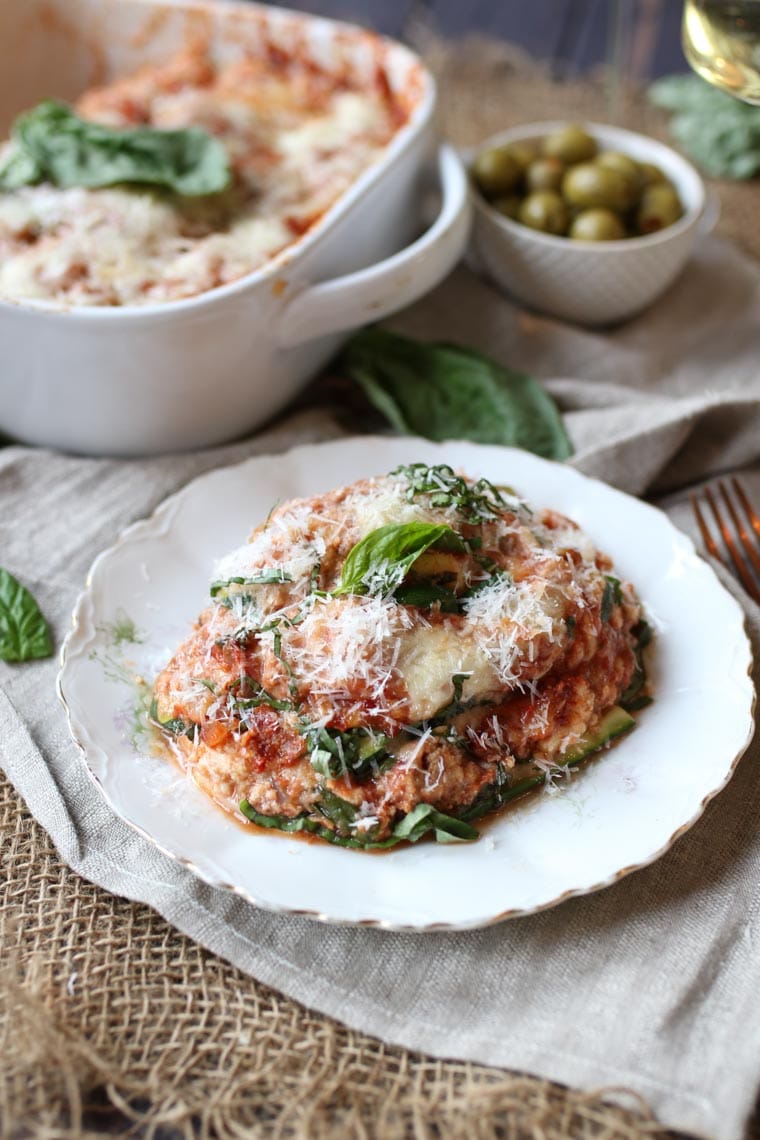 A plate of zucchini lasagna with basil and cheese grated on top.