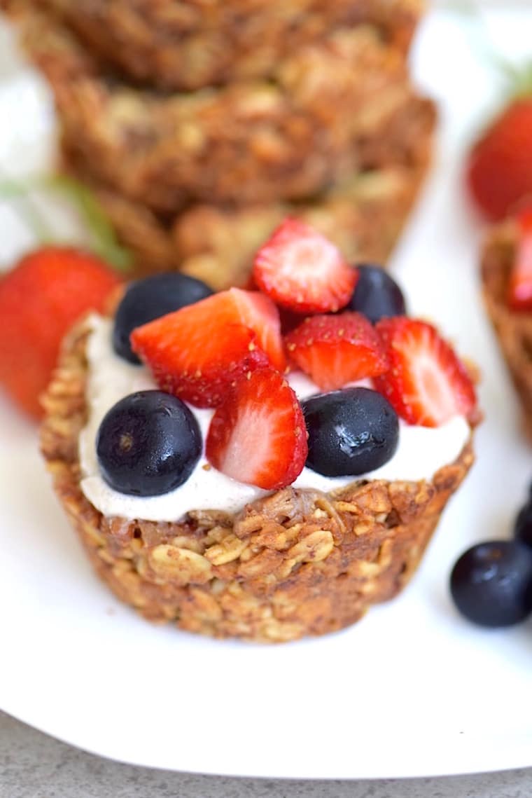 close up of vegan granola cup with banana cream garnished with fresh berries on a white plate