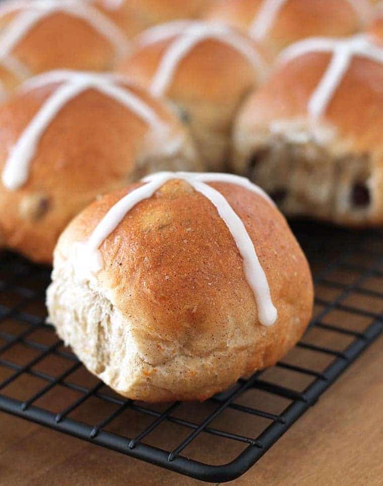 close up shot of multiple vegan hot cross buns laid on a black cooling tray