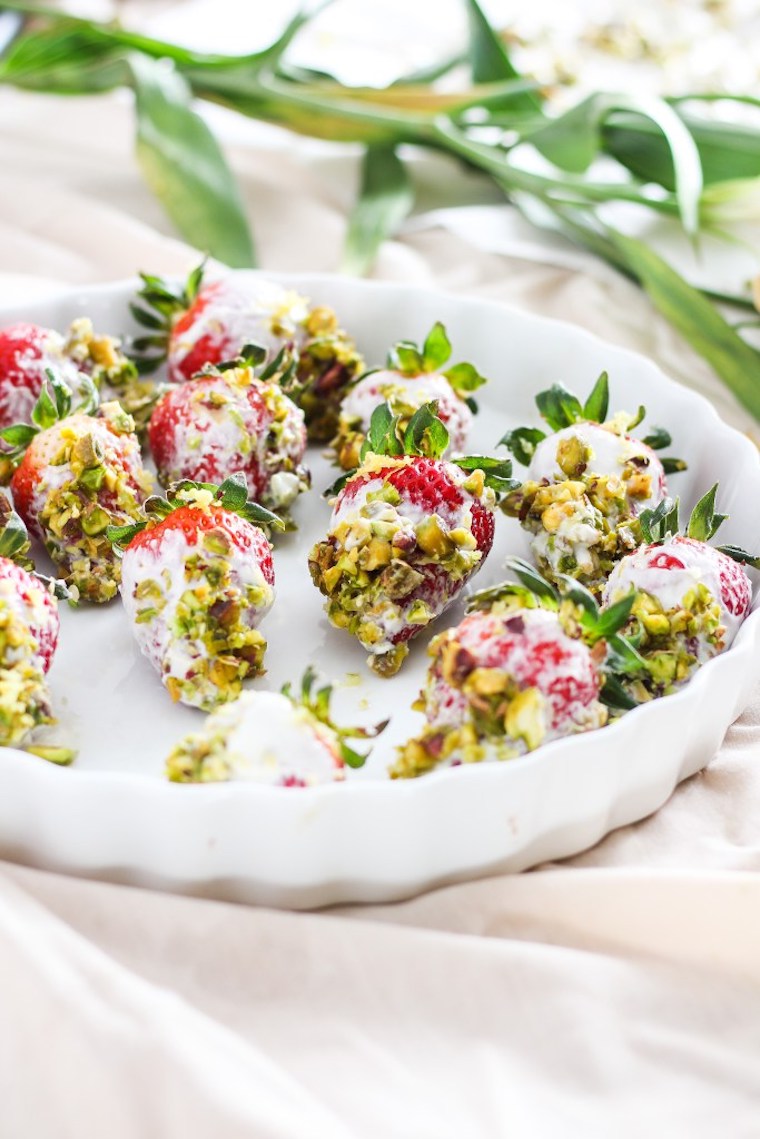 white serving plate with multiple vegan pistachio yogurt dipped strawberries