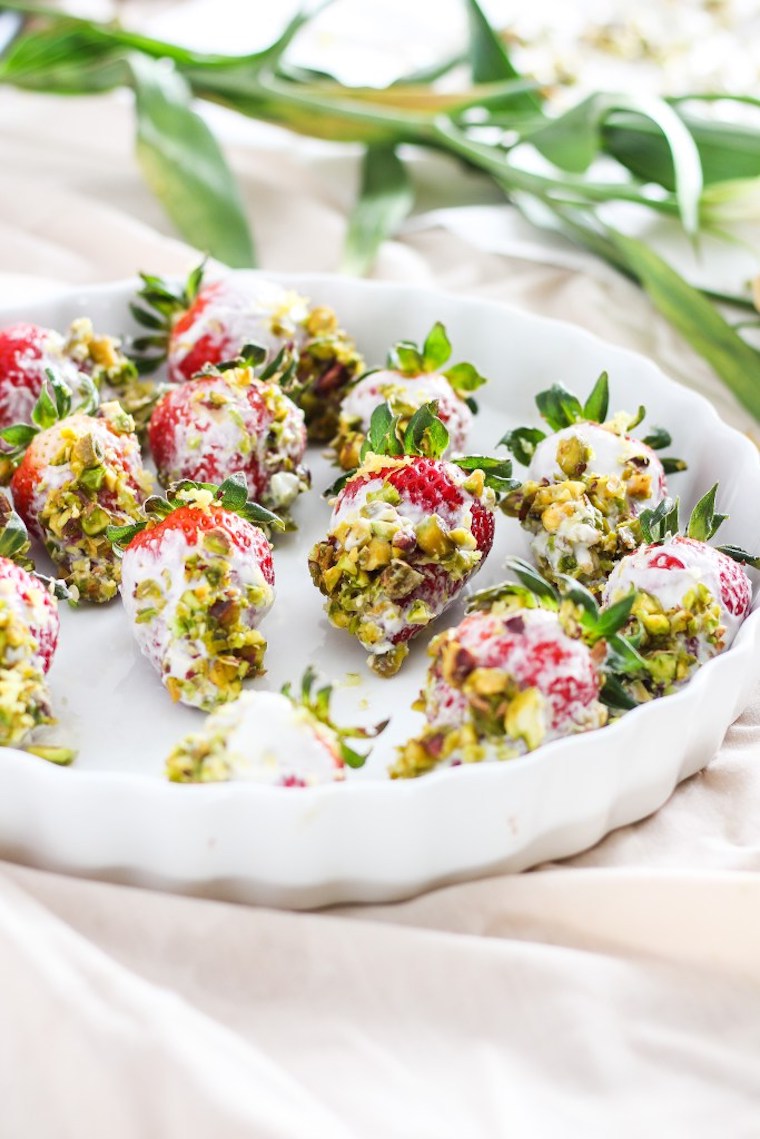 white serving plate with multiple vegan pistachio yogurt dipped strawberries 