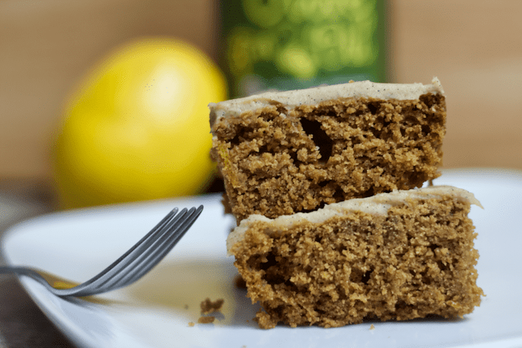 close up of vegan and gluten free lemon and olive oil cake on a white plate with a silver fork next on the plate