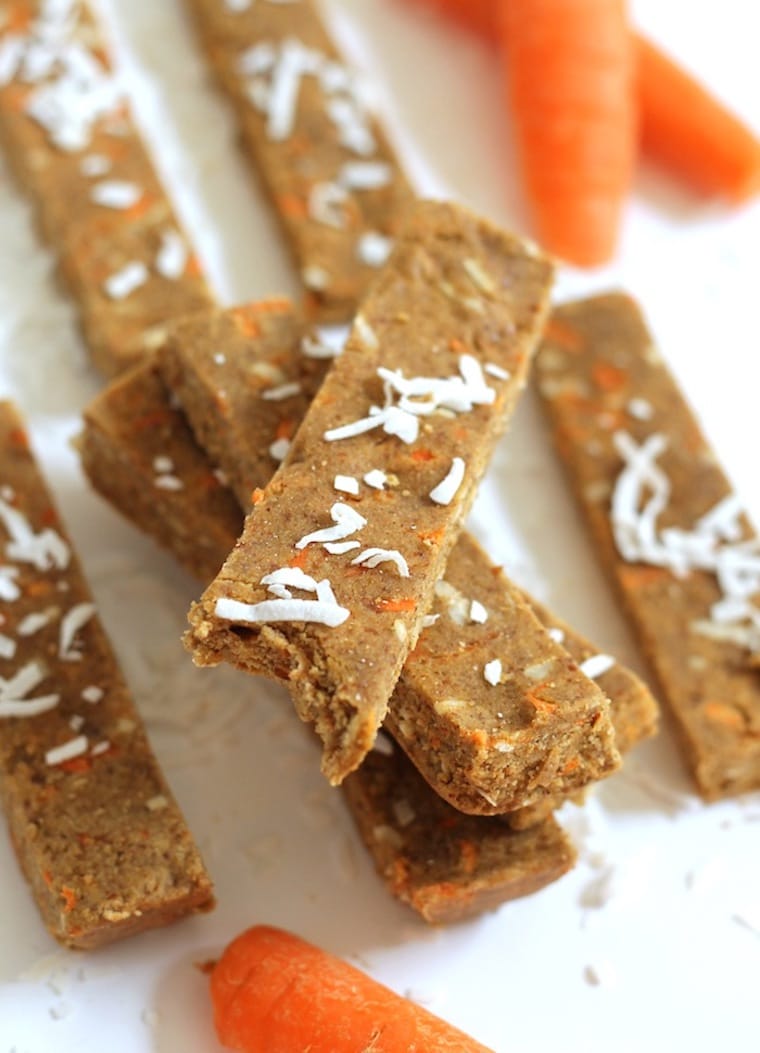 stack of vegan gluten free carrot cake protein bars garnished with fresh coconut on a white background