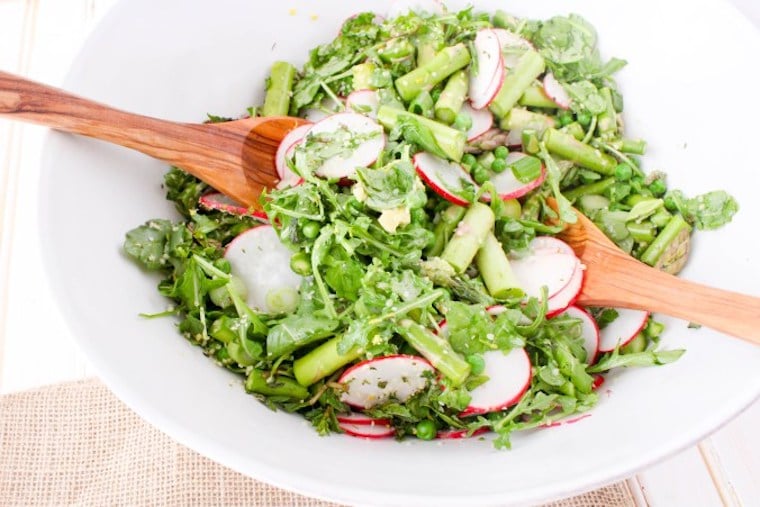 gluten free and vegan asparagus salad for springtime topped with lemon hemp dressing presented in a white bowl with wooden serving spoons