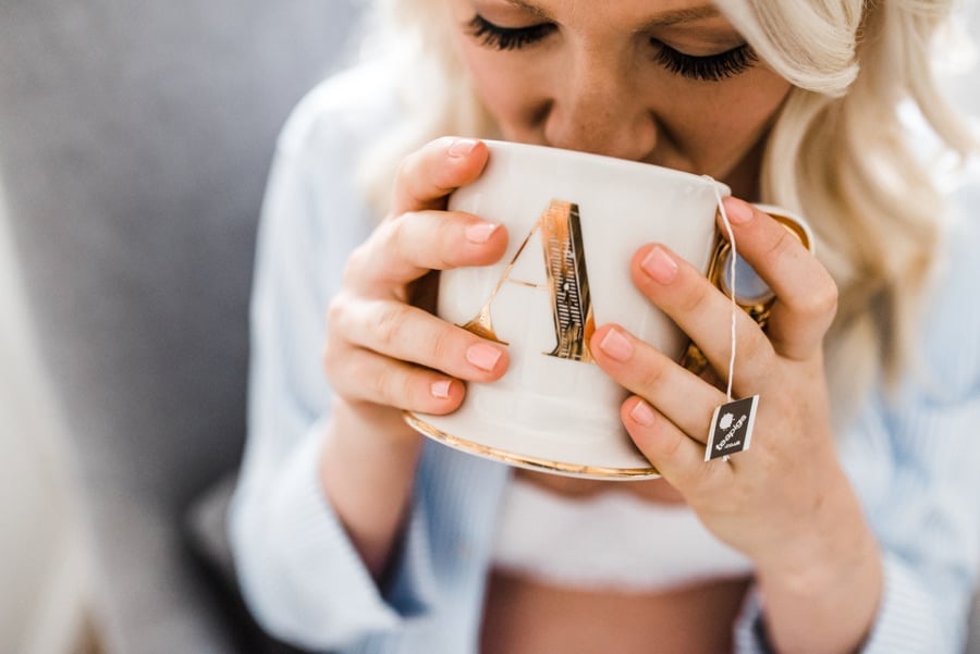 Woman drinking herbal tea from a mug with a tea bag for pregnancy food safety.