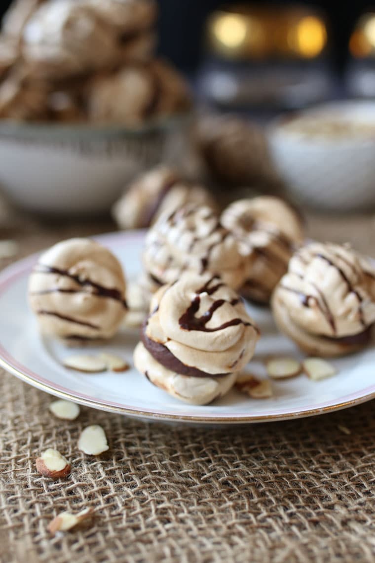 A plate with almond cherry chocolate meringue cookies with a chocolate ganache.