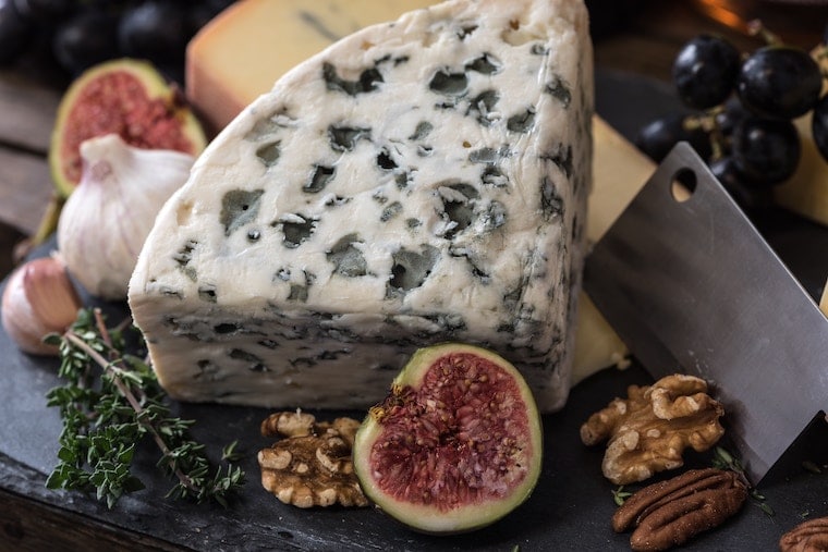 Plate of blue cheese, figs, walnuts, pecans and others foods that are not allowed for pregnancy food safety.