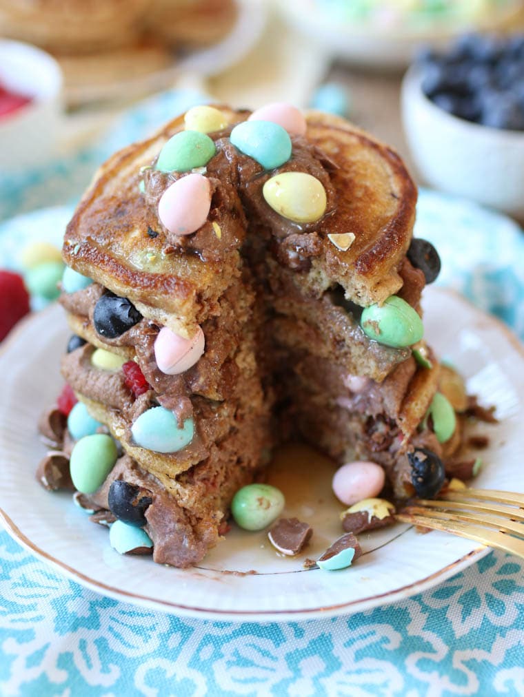 An image of a cut open stack of mini egg pancakes with raspberries and blueberries in between.