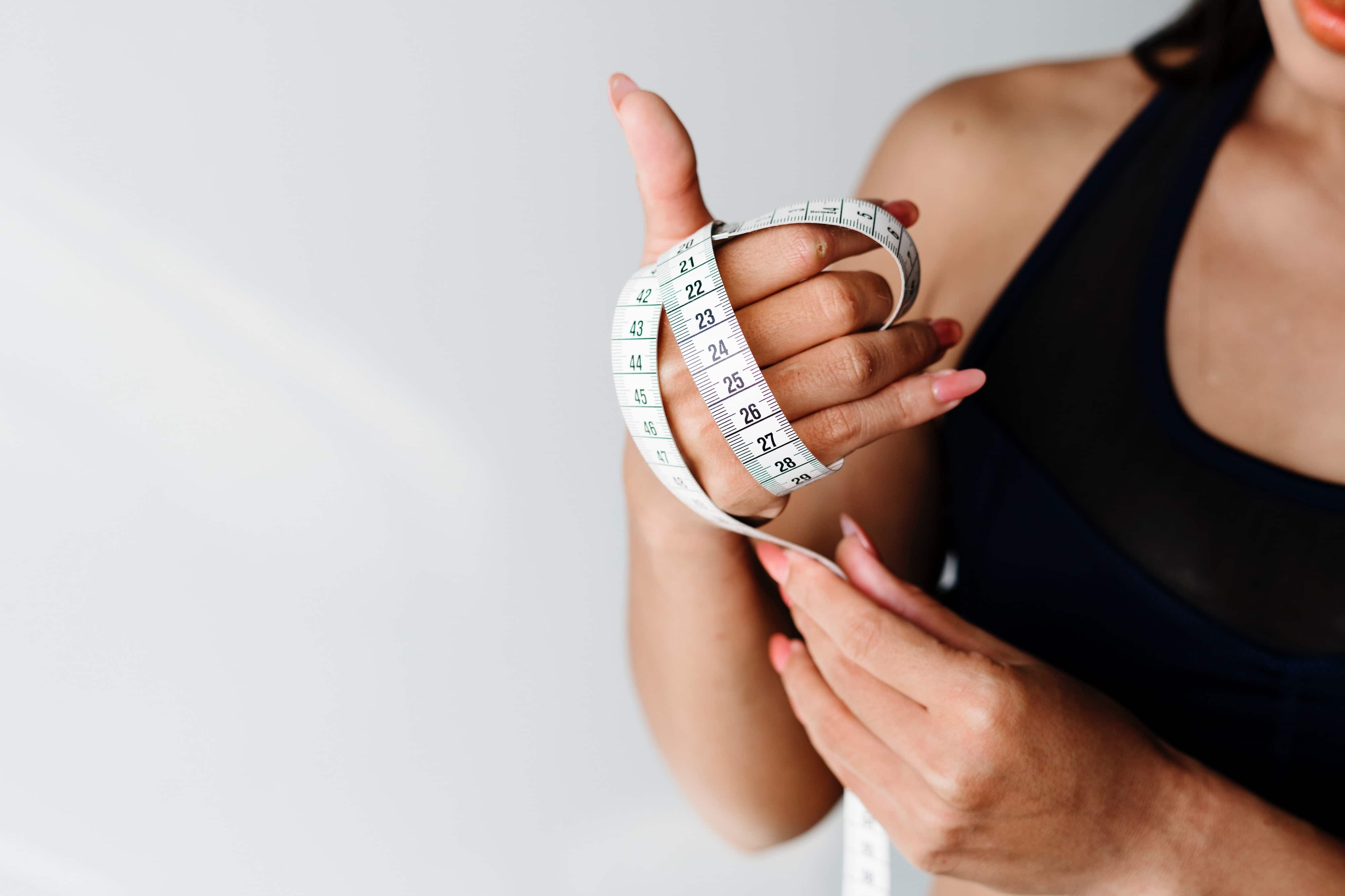 Woman looking at measuring tape to measure weight loss.