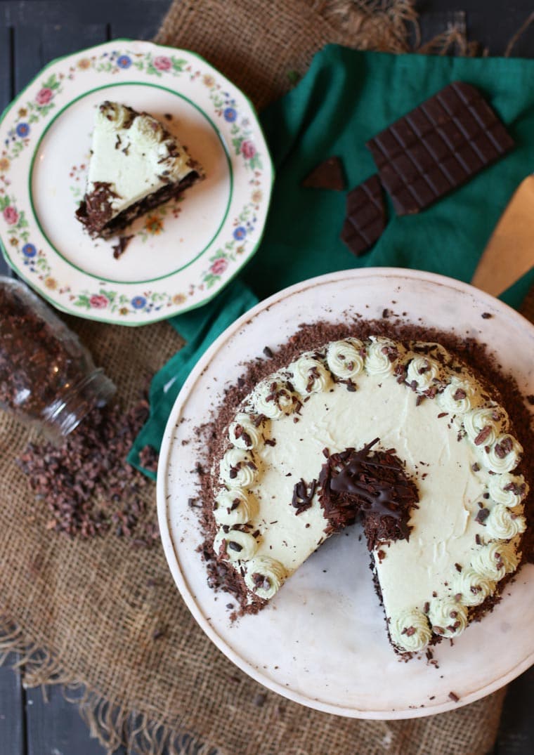 An overhead image of a chocolate mint cake with a slice cut out of it.